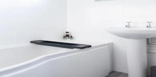 La salle de bains blanche est pourvue d'un lavabo et d'un lavabo blancs. dans l'établissement RueVizelleChalet FantasticChalet, à Courchevel