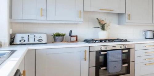 une cuisine avec des armoires blanches et un four à plaques de cuisson dans l'établissement RueVizelleChalet FantasticChalet, à Courchevel