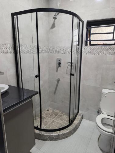 a shower stall in a bathroom with a toilet at Taurus Apartments in Chipata