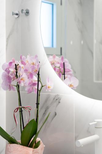 a vase of pink flowers in a bathroom at Frunze Luxury Apartments in Nafplio