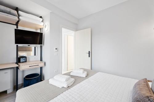 a white bedroom with a bed and a tv at Frunze Luxury Apartments in Nafplio