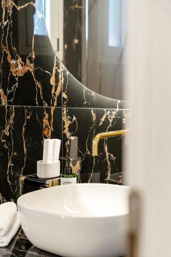 a bathroom with a white sink and a black wall at Frunze Luxury Apartments in Nafplio