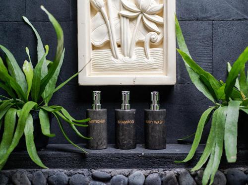 a group of four bottles on a shelf next to plants at The Manja Retreat Lovina in Buleleng