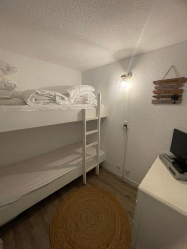 une petite chambre avec un lit, un bureau et un tapis dans l'établissement Location Studio Cabine St Lary Soulan, à Saint-Lary-Soulan