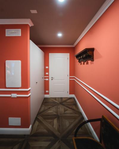a hallway with orange walls and a white door at Locanda Gaudemus Boutique Hotel in Sistiana