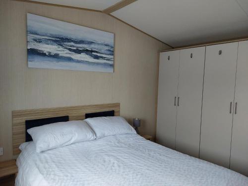 Un dormitorio con una cama y un cuadro en la pared. en Gateway to Cornwall, en St Austell