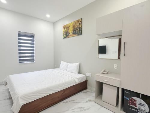 a white bedroom with a bed and a mirror at Anh Thư Hotel in Ấp Bình Hưng