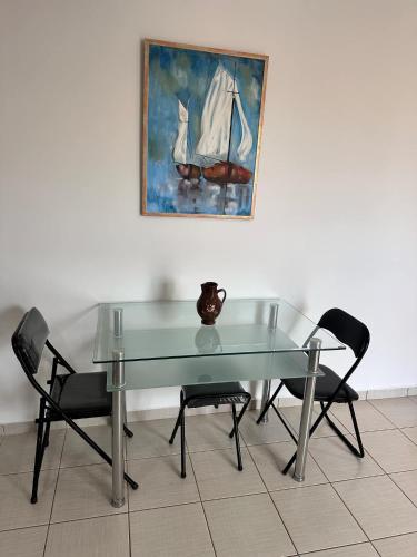 a glass table with two chairs and a vase on it at Captain's Lodge in Ermoupoli