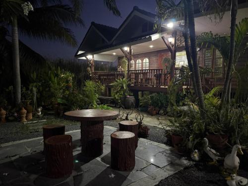 a patio with a table and stools in front of a house at House in the garden in Phitsanulok