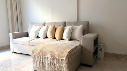 a white couch with pillows on it in a living room at Near City Centre Mall, Pool, Gym in Muscat