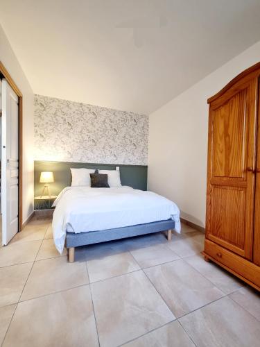 une chambre avec un lit blanc et une armoire en bois dans l'établissement Maison au cœur de la Côte D'Opale, à Bellebrune