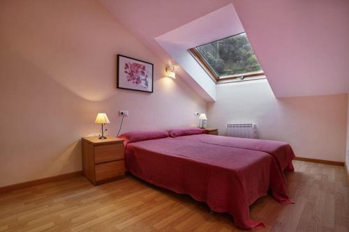 a bedroom with a red bed and a window at Urbanización Barrio de Triana 3c in Nueva de Llanes