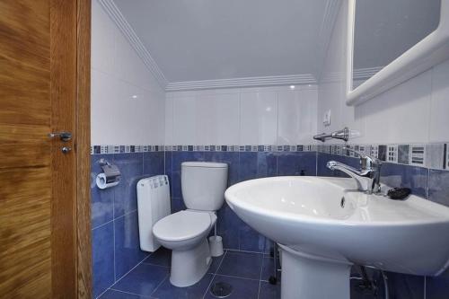 a bathroom with a white toilet and a sink at Urbanización Barrio de Triana 3c in Nueva de Llanes