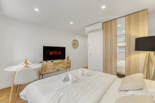 Cette chambre blanche dispose de 2 lits et d'une télévision. dans l'établissement Magnifique studio Macé, à Cannes