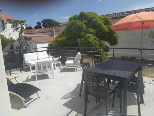 - une table, des chaises et un parasol sur la terrasse dans l'établissement Maison à 100m de la plage, à Longeville-sur-Mer