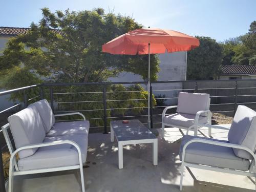 un patio avec deux chaises, une table et un parasol dans l'établissement Maison à 100m de la plage, à Longeville-sur-Mer