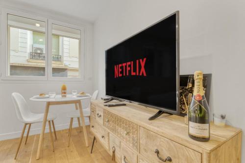 Elle comprend une télévision à écran plat installée au-dessus d'une commode en bois. dans l'établissement Magnifique studio Macé, à Cannes