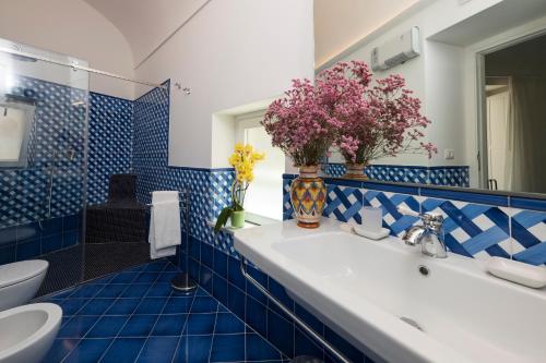 a blue tiled bathroom with a sink and a toilet at Secret Amalfi - Your stay in downtown Amalfi in Amalfi