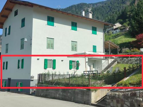 a white house with green windows and a fence at Appartamento Maria in Canale San Bovo