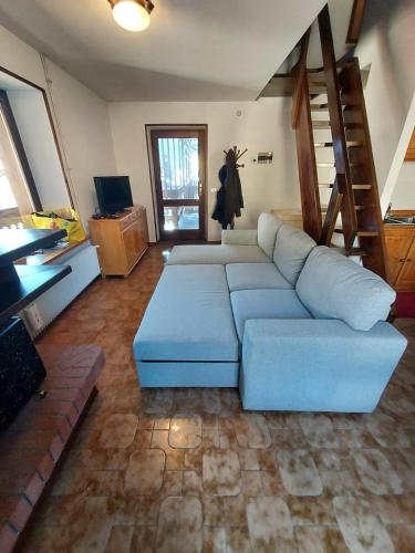 a living room with a blue couch and a staircase at Oasis House in Forni di Sopra