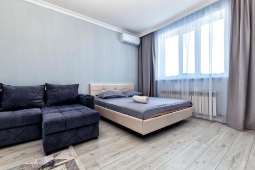 a bedroom with a bed and a couch and a window at Уютная кв в ЖК Комсомольский in Taldykolʼ