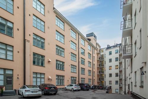 a row of buildings with cars parked in a parking lot at Scandinavian attic apartment in the city center in Helsinki