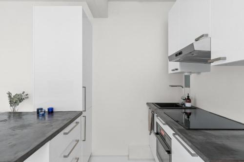 a kitchen with white cabinets and a stainless steel counter top at Scandinavian attic apartment in the city center in Helsinki