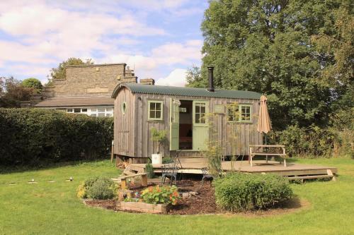 a small shed with a bench in a yard at Luxury Shepherds Hut in Stonehouse