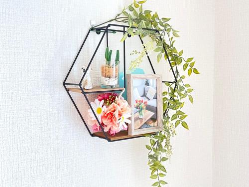 a hanging shelf with flowers and plants on a wall at Highness Gojo in Dazaifu