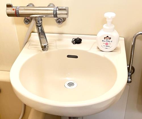a bathroom sink with a bottle of detergent on it at Highness Gojo in Dazaifu