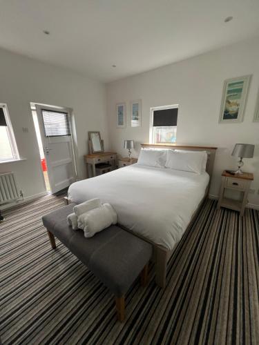 a bedroom with a large white bed and a bench at Beechwood Lodges in Ballycastle