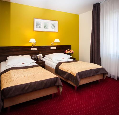 two beds in a hotel room with yellow walls at Hotel Pikul in Puławy