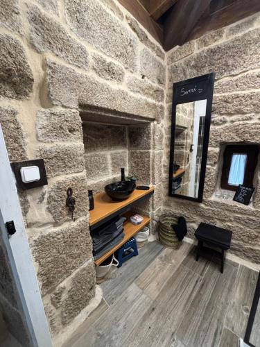 y baño con pared de piedra, tocador y espejo. en Aturuxo VUT OR 994, en Trasmiras