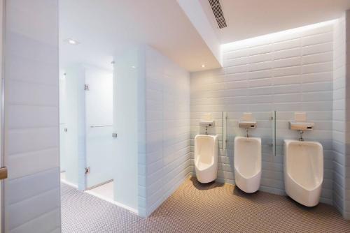 three urinals in a bathroom with white tiles at 苓旅松山館 Lininn Tapei Arena in Taipei