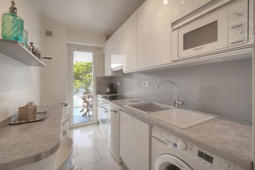 une cuisine blanche avec un évier et un lave-vaisselle dans l'établissement FRGK Rochelongue Vue Mer Panoramique, Terrasse & Plage Privée, à Cannes