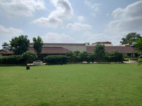 a large grassy field in front of a building at The Fern Sattva Resort - Polo Forest in Vijayanagar
