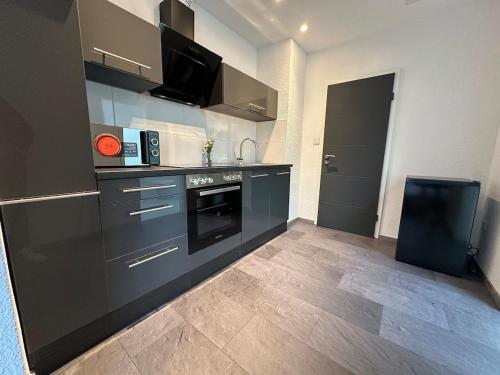メンヒェングラートバッハにあるBeautiful Appartment in MG - Self Check-inのキッチン(黒いキャビネット、黒いオーブン付)