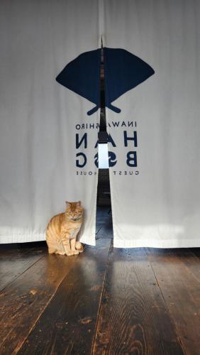 a cat sitting on the floor next to a wall with an umbrella at Guest House Inawashiro~Hanbog~ in Inawashiro