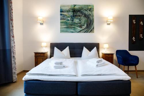 a bedroom with a bed with white sheets and two chairs at Hotel 1912 in Angermünde