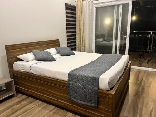 a bedroom with a large bed with white sheets and blue pillows at Avalon Stays in Guwahati
