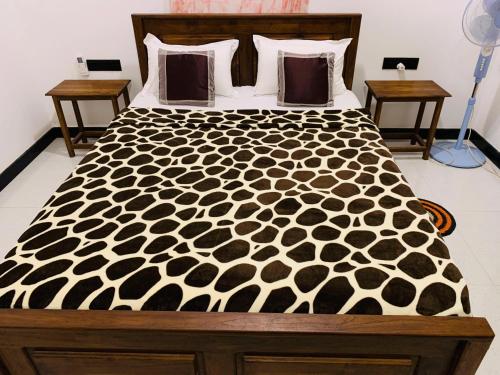 a large bed with a black and white comforter at Nature World Udawalawe in Udawalawe