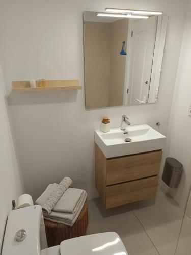 a bathroom with a sink and a toilet and a mirror at Camí Ample, Apartamento 2 hab con parking in L'Escala