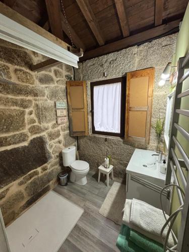 a stone bathroom with a toilet and a sink at Casa Escuela Trasmiras in Trasmiras