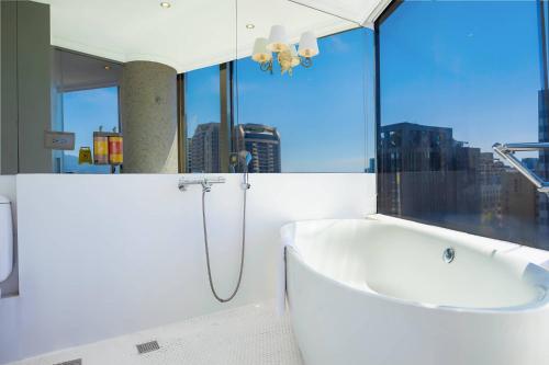 a bathroom with a bath tub and a window at 苓旅松山館 Lininn Tapei Arena in Taipei