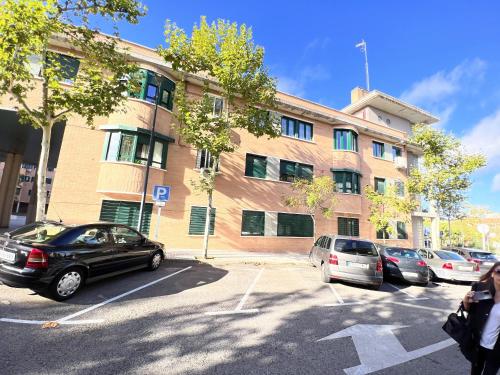 a parking lot with cars parked in front of a building at A&R Santiago de Compostela in San Sebastián de los Reyes