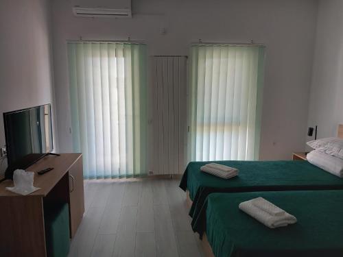 a hotel room with two beds and a television at Pensiunea Crama Pivnițele Niculițel in Niculiţel
