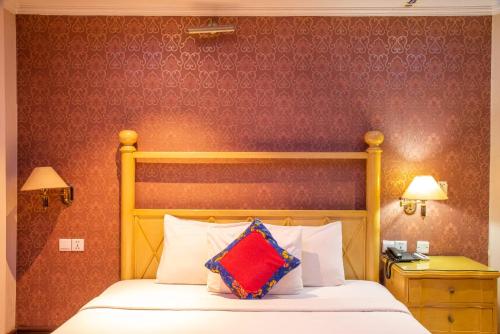 a bed with a yellow headboard and a red pillow at Sea Shell Residence - Dhaka in Dhaka