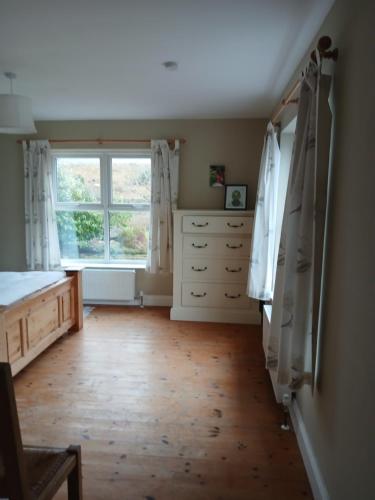 a bedroom with a bed and a dresser and a window at Watersedge in Mulranny
