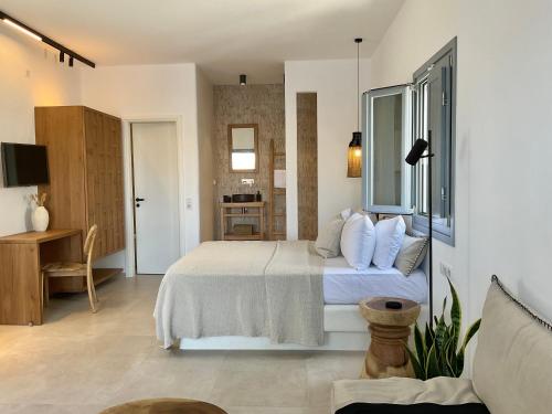 a bedroom with a bed with white sheets and a desk at Salvia di Astypalea in Livadi Astypalaias