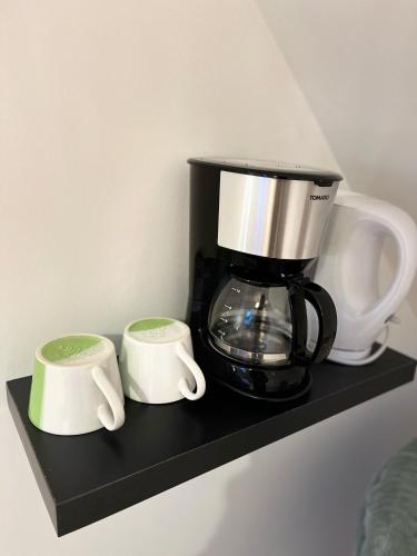 une cafetière et deux tasses sur une étagère dans l'établissement Les gîtes du Mesnil chambre deluxe, à Équemauville